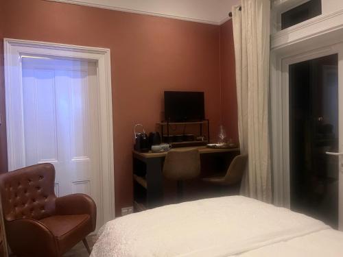 a bedroom with a bed and a desk with a television at Staincliff House in Sandown