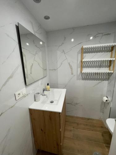 a white bathroom with a sink and a mirror at Apartamento las OLAS playa de levante in Benidorm