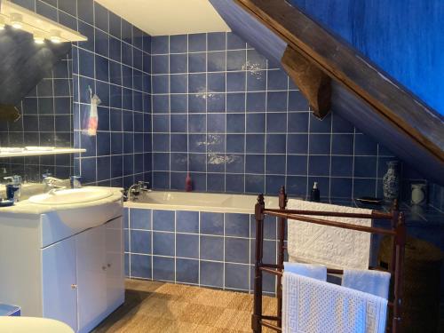 uma casa de banho em azulejos azuis com um lavatório e uma banheira em Les ateliers d’Aumâtre em Aumâtre