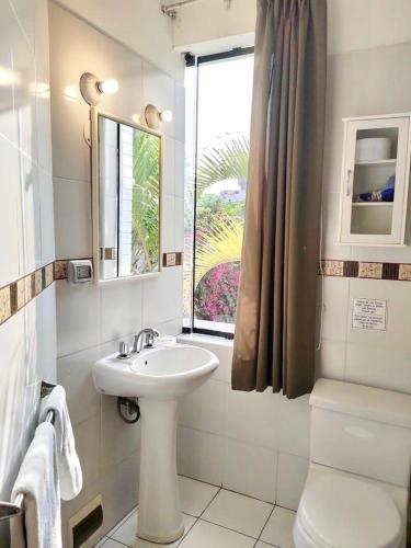 a white bathroom with a sink and a window at Casa Bella Boutique Hotel San Isidro in Lima
