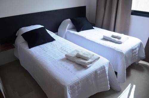 House and Suite Premium في سانتا في: سريرين عليها شراشف بيضاء ومناشف