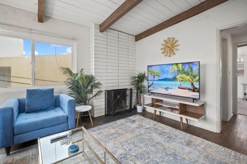 een woonkamer met een tv en een blauwe stoel bij NEW! Ocean View Mid-Century Modern Beach House in Manhattan Beach