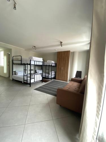 The Point Miraflores - Party Hostel في ليما: غرفة معيشة مع سريرين بطابقين وأريكة