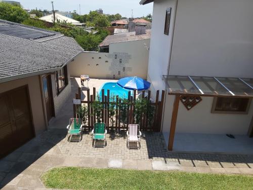 eine Terrasse mit Stühlen, einem Sonnenschirm und einem Pool in der Unterkunft SOBRADO COM PISCINA in Arroio do Sal