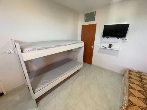 Una pequeña habitación con una litera y un televisor. en Central Praias Suíte 2, en Cabo Frío