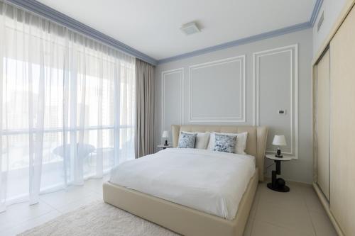a white bedroom with a large bed and large windows at Palmar One Bedroom with Private Beach! in Dubai