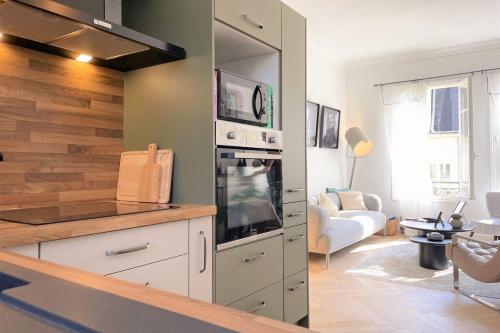 Il comprend une cuisine équipée d'une cuisinière. - un four supérieur à côté d'un salon dans l'établissement Le Vertigo - Standing - Proche Mairie, à Caen