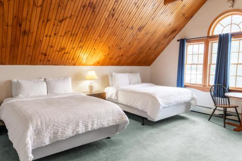 2 łóżka w pokoju z drewnianym sufitem w obiekcie Sara Placid Inn & Suites w mieście Saranac Lake