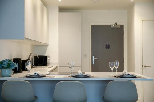 uma cozinha com uma mesa com copos de vinho em Trafford Suite Modern 1 bed with cinema room em Manchester