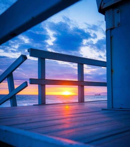 a wooden deck with a view of the sunset at Brand New Ocean-View Beach Home Steps to the Sand! in Manhattan Beach