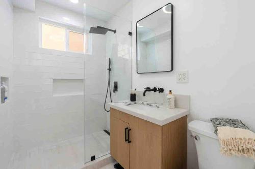 La salle de bains est pourvue d'une douche, d'un lavabo et d'un miroir. dans l'établissement Brand New Ocean-View Beach Home Steps to the Sand!, à Manhattan Beach