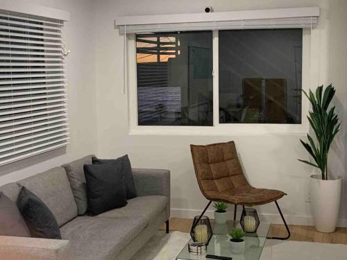 a living room with a couch and a chair and a window at Brand New Ocean-View Beach Home Steps to the Sand! in Manhattan Beach