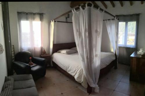 - une chambre avec un lit à baldaquin et une chaise dans l'établissement Belle Villa à la campagne avec piscine, à Brue-Auriac