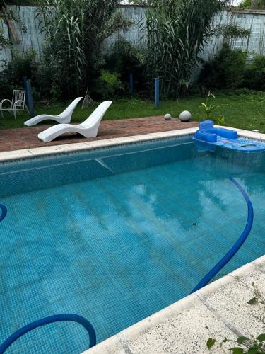 una piscina con 2 sillas blancas en un patio en Rosadita loft en Río Ceballos