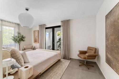 een witte slaapkamer met een bed en een stoel bij Casa Loba Luxe Apartment with pool and ocean views in Rincon