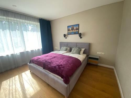 a bedroom with a large bed with a purple blanket at Apartamentai Ornamentai in Druskininkai