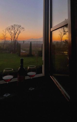two glasses of wine sitting on a window sill with the sunset at Appartamento in Villa Aulla in Pontedera
