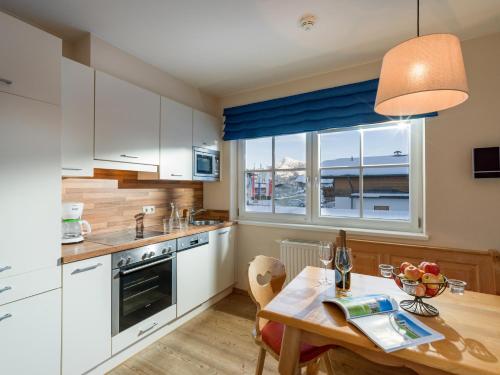 a kitchen with white cabinets and a table and a window at Alpen Glück Hotel Villa Lisa garni in Kirchberg in Tirol