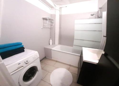 un bagno bianco con lavatrice e vasca di Appartement spacieux et lumineux - 15min de Paris Centre - Ideal Olympics a Sartrouville