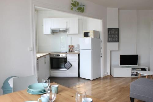 una cucina con tavolo e frigorifero bianco di Appartement spacieux et lumineux - 15min de Paris Centre - Ideal Olympics a Sartrouville