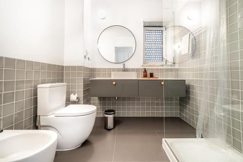 La salle de bains est pourvue de toilettes, d'un lavabo et d'un miroir. dans l'établissement BeGuest Falesia Beach & Garden, à Albufeira
