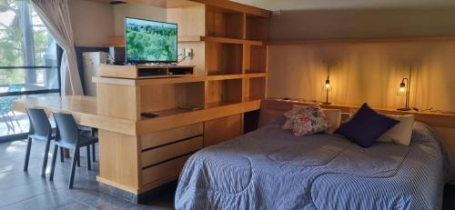 Un dormitorio con una cama y un escritorio con televisión. en APART CLUB SAN PEDRO Loft, en San Pedro