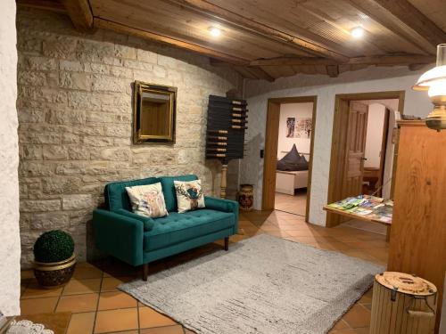 a living room with a green couch and a stone wall at Altmuehl Familienvilla in Treuchtlingen