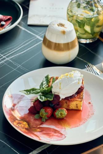 a plate with a piece of cake with strawberries and whipped cream at La Fleur Boutique Hotel in Tivat