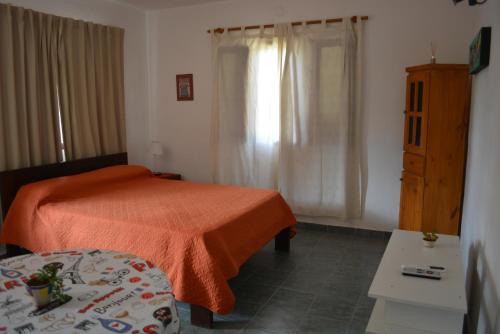 1 dormitorio con 1 cama con manta naranja en Cabaña El Canal en Villa Carlos Paz