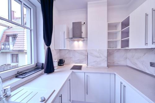 cocina blanca con armarios blancos y ventana en LAGUNA Apartament Willa Ogrodowa 17 en Polanica-Zdrój