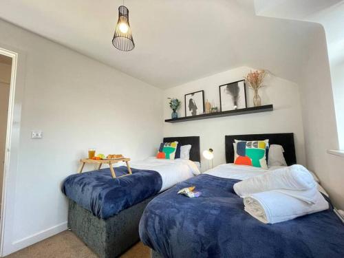 Urban Oasis in Lively Selly Oak! في برمنغهام: غرفة نوم بسريرين عليها اغطيه زرقاء