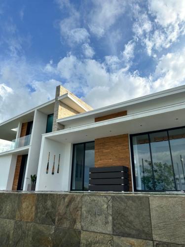 a white house with glass windows and a stone wall at PASSOT HILLS in Nosy Be