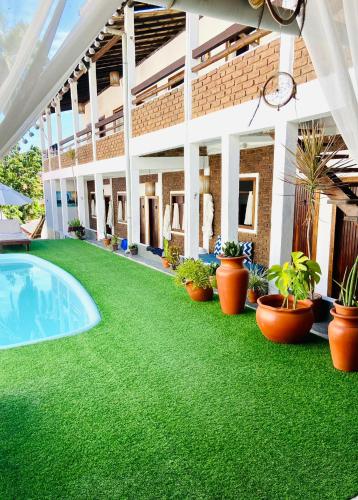 a yard with green grass and a swimming pool at Pousada Arraial da Poesia in Arraial d'Ajuda