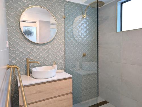 uma casa de banho com um lavatório e um espelho em Whale Tail Beach House em Pambula Beach