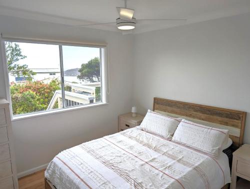a bedroom with a bed and a large window at Whale Tail Beach House in Pambula Beach