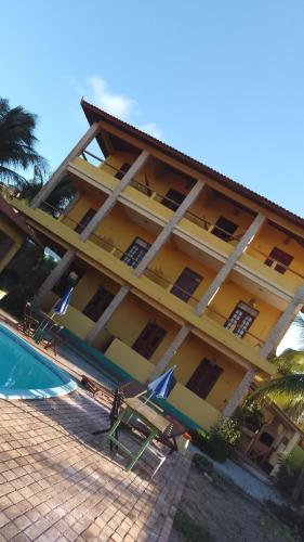 a large yellow building with a swimming pool in front of it at Village Lagoinha Ceará in Tigre