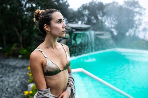a woman in a bikini standing next to a swimming pool at Hotel Termales del Ruiz in Manizales