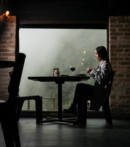a woman sitting at a table with a glass of wine at Hotel Termales del Ruiz in Manizales