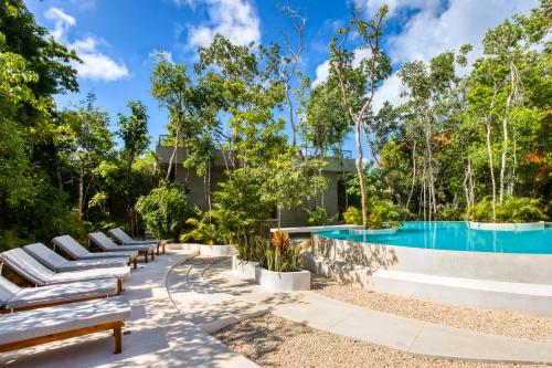 een rij banken naast een zwembad bij Original studios by Casago in Tulum