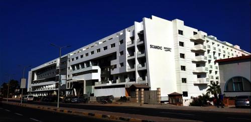 a large white building with cars parked in front of it at Scandic Resort Apartment B 608 Hurghada in Hurghada