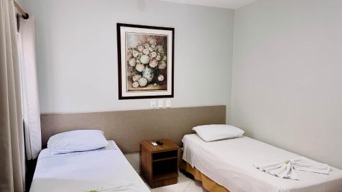 two beds in a room with a picture on the wall at GB Hotéis Foz in Foz do Iguaçu