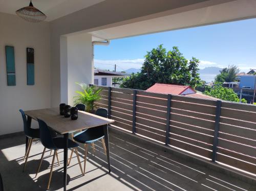 un tavolo e sedie su un balcone con vista di Le Fare Cosy Kiwi et le Fare Cosy Tiki a Faaa