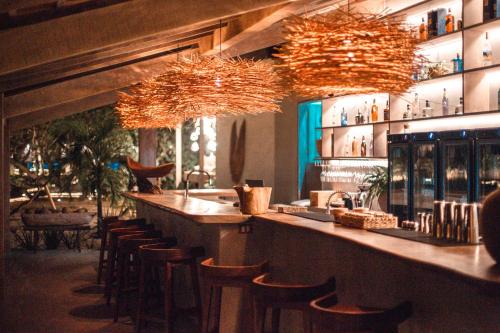 un bar con taburetes y lámparas de araña en un restaurante en Anacardier Privé Hotel, en Atins