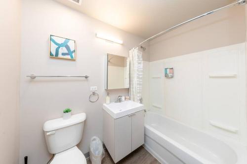 a white bathroom with a toilet and a sink at McCormick 2br/2ba Oasis with optional Parking, Patio, Gym for up to 6 guests in Chicago