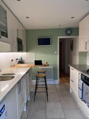 a kitchen with white cabinets and a stool in it at Kemp Town apartment in Brighton & Hove