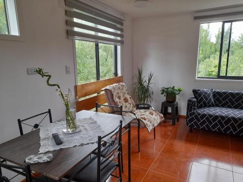 un salon avec une table, des chaises et un canapé dans l'établissement Apartamentos Vera Ribbeck, à Valdivia