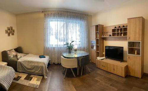 een woonkamer met een tafel, een televisie en een raam bij Studio apartamenti Cēsis in Cēsis