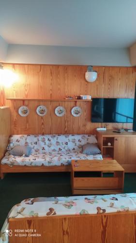 een slaapkamer met 2 bedden en een houten muur bij Appartamento Marilleva1400 residence Albarè in Marilleva