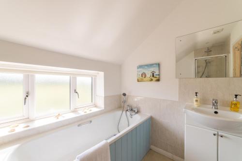 a white bathroom with a sink and a window at Holly Cottage, Surrey Hills in Cranleigh