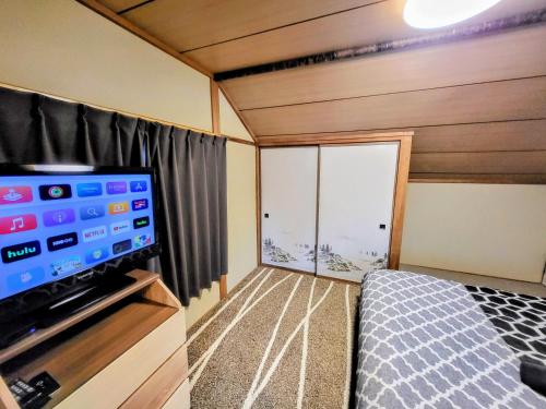 Habitación pequeña con TV de pantalla plana y cama en Powder Peak Misorano Free courtesy car en Hakuba